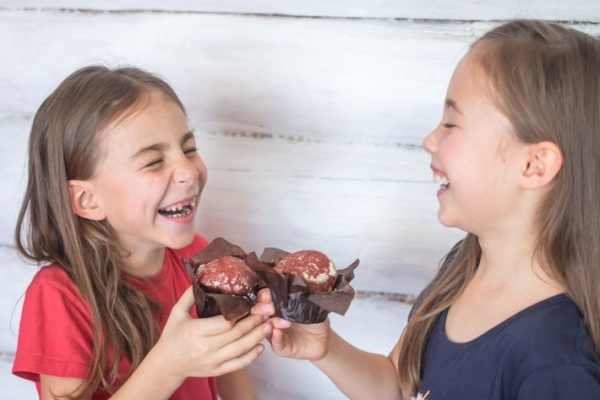Kids laughing and eating chocolate muffins at a birthday party.